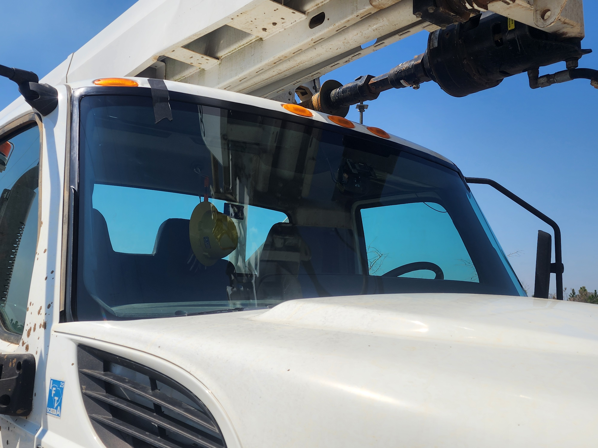 Side view mirror on a white vehicle, against a cloudy sky.
