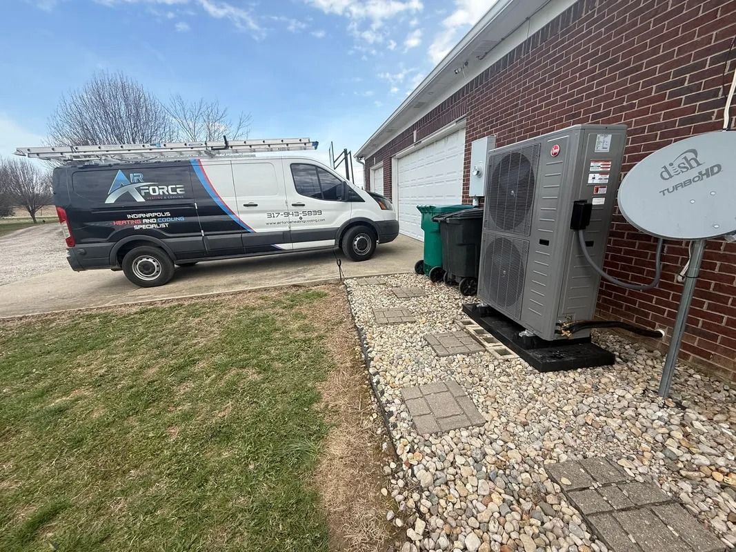 Service van parked beside a brick house, with trash bins and a satellite dish along the side yard.
