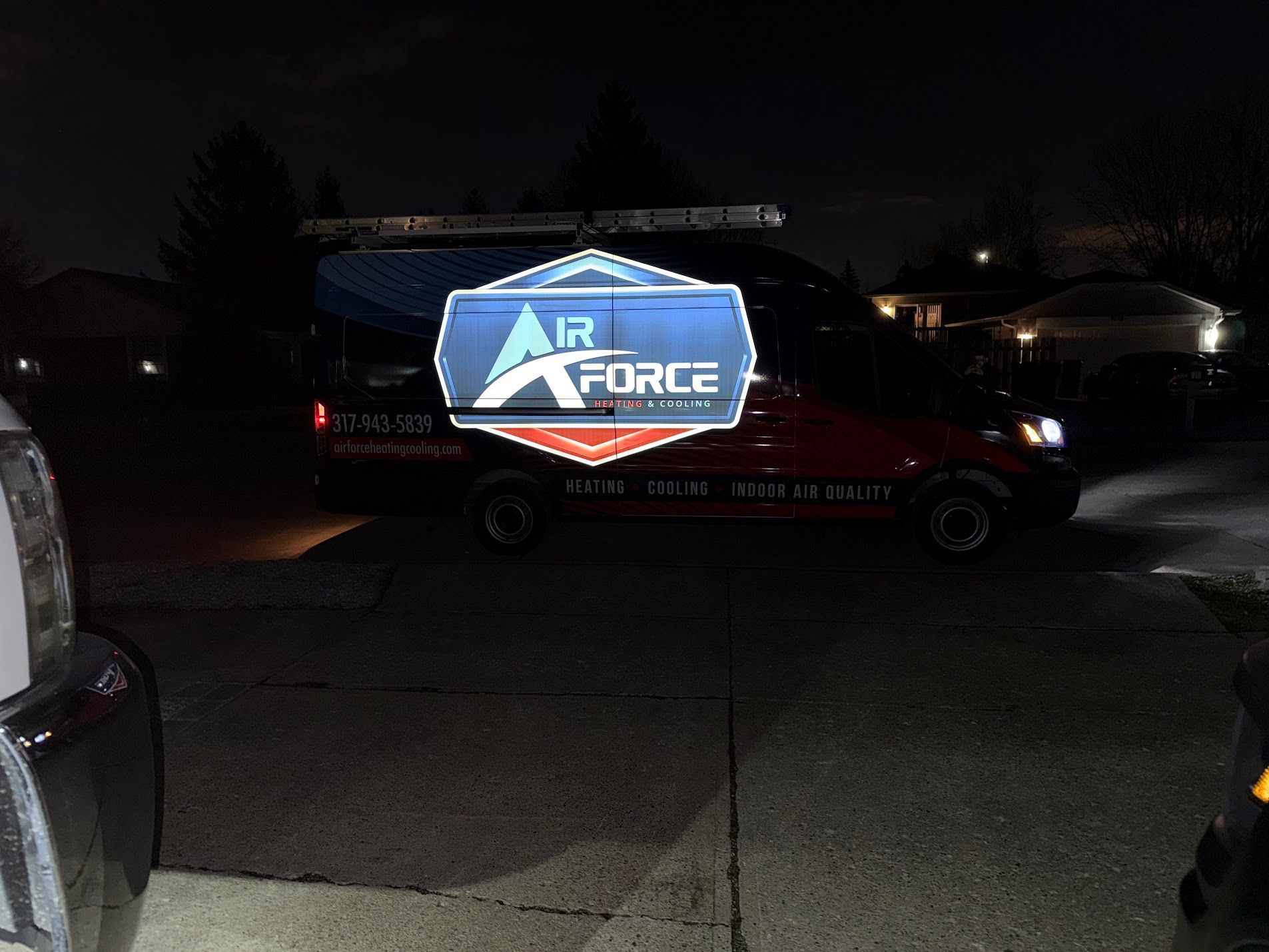 Air Force-branded van parked at night in a dim residential driveway