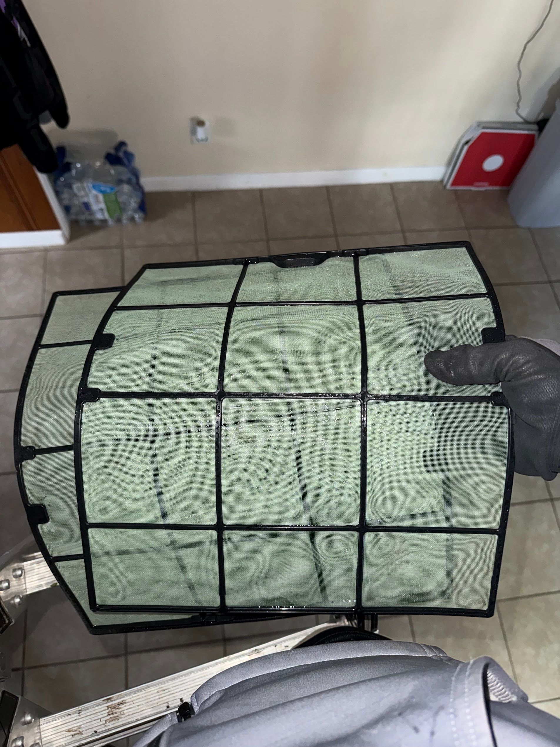 Black pet gate surrounding a green blanket-covered object on a tiled floor indoors.