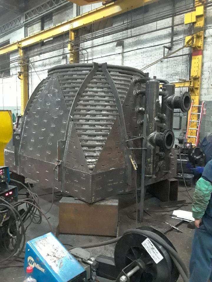 Large industrial metal structure with curved tubes, in a workshop setting.