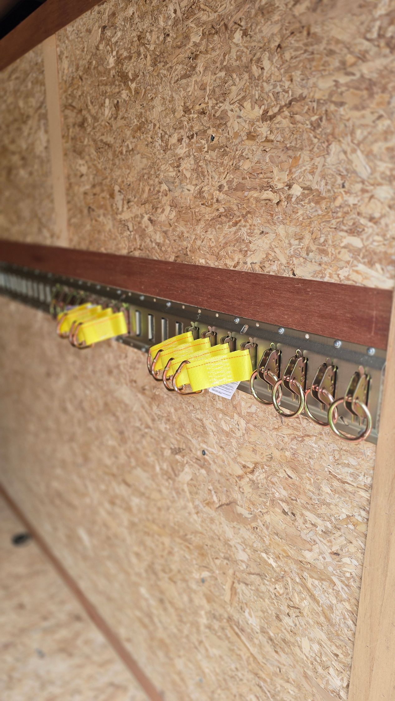 Close-up of a wooden board with a horizontal metal strip and yellow clips attached.