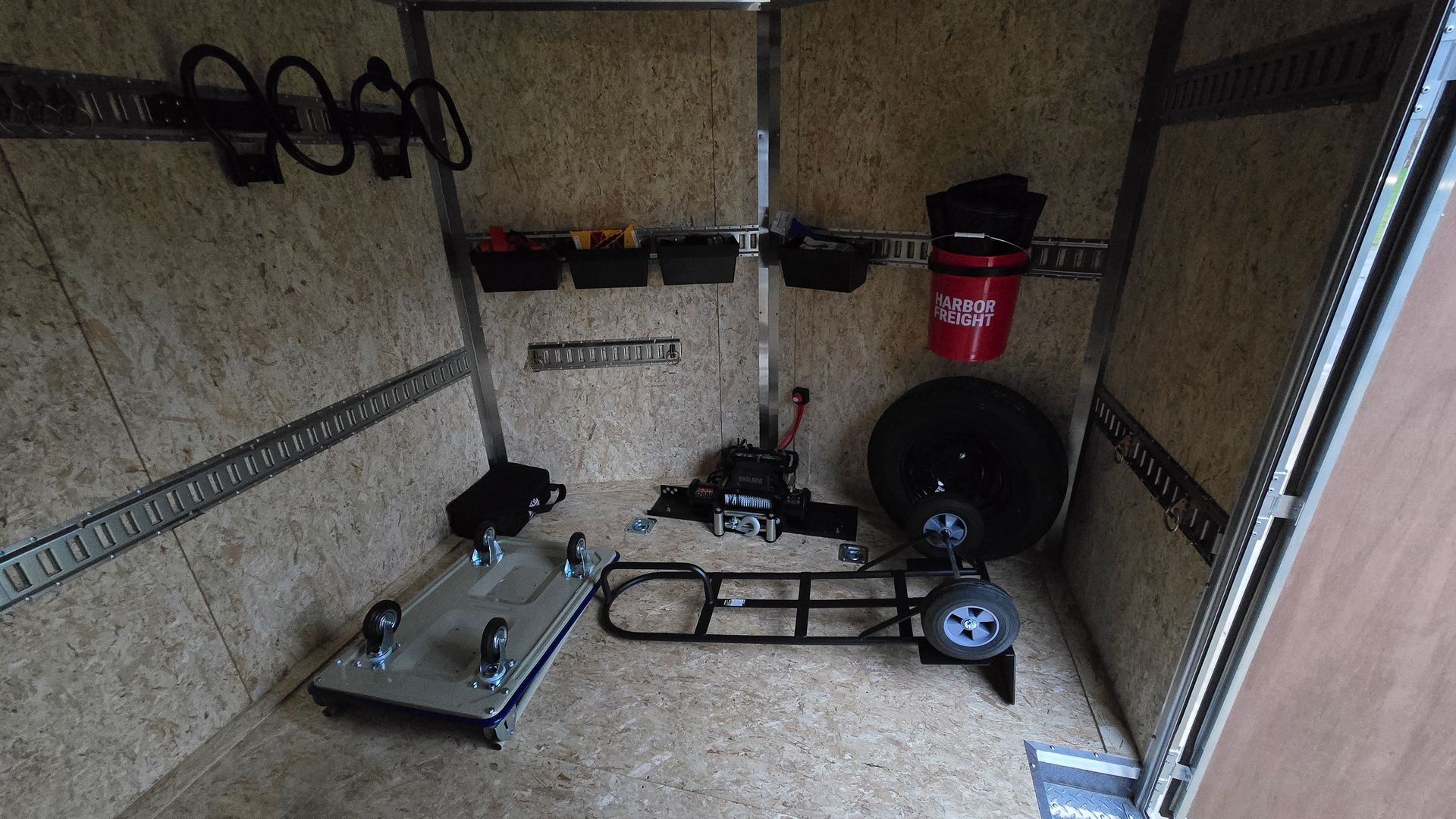 Empty garage with exercise equipment, a red vacuum, and a black wheel on the floor.