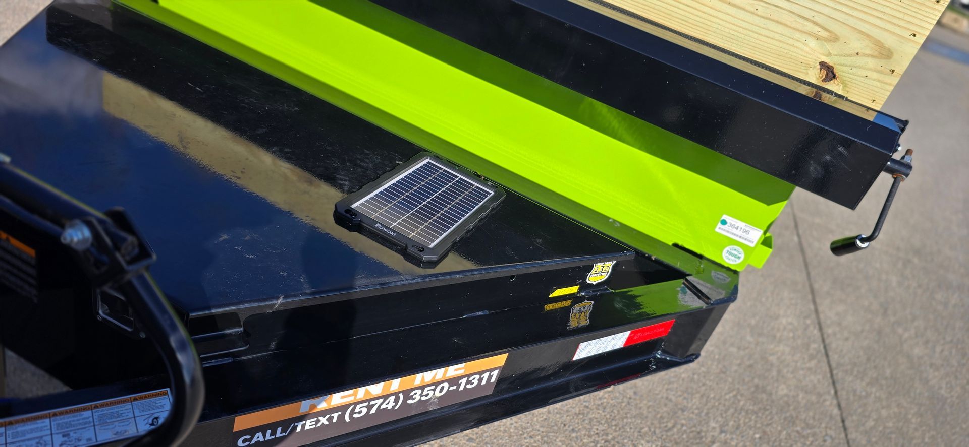 Bright green metal trailer ramp with wooden planks on a black utility trailer