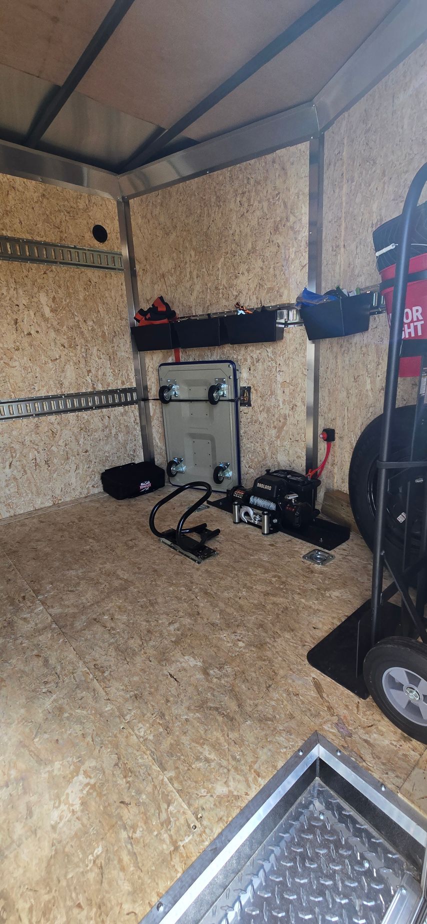 Inside a small equipment room with acoustic walls, a drum kit, cables, and speakers set up near the back wall.