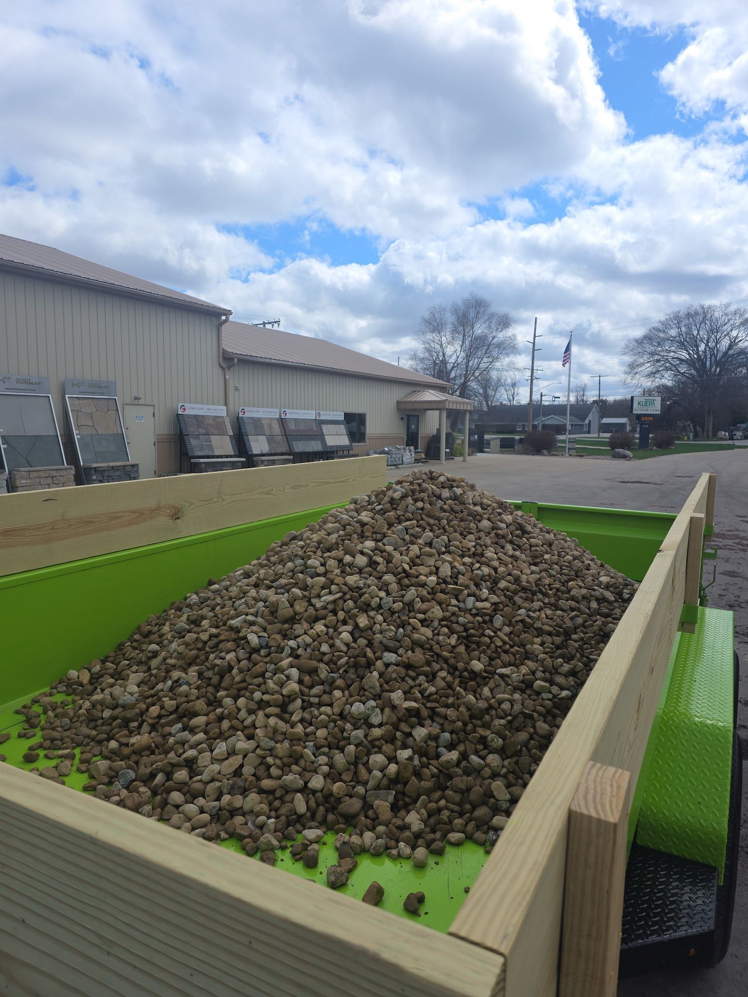 Truck bed piled high with rocks at an industrial yard under a cloudy sky