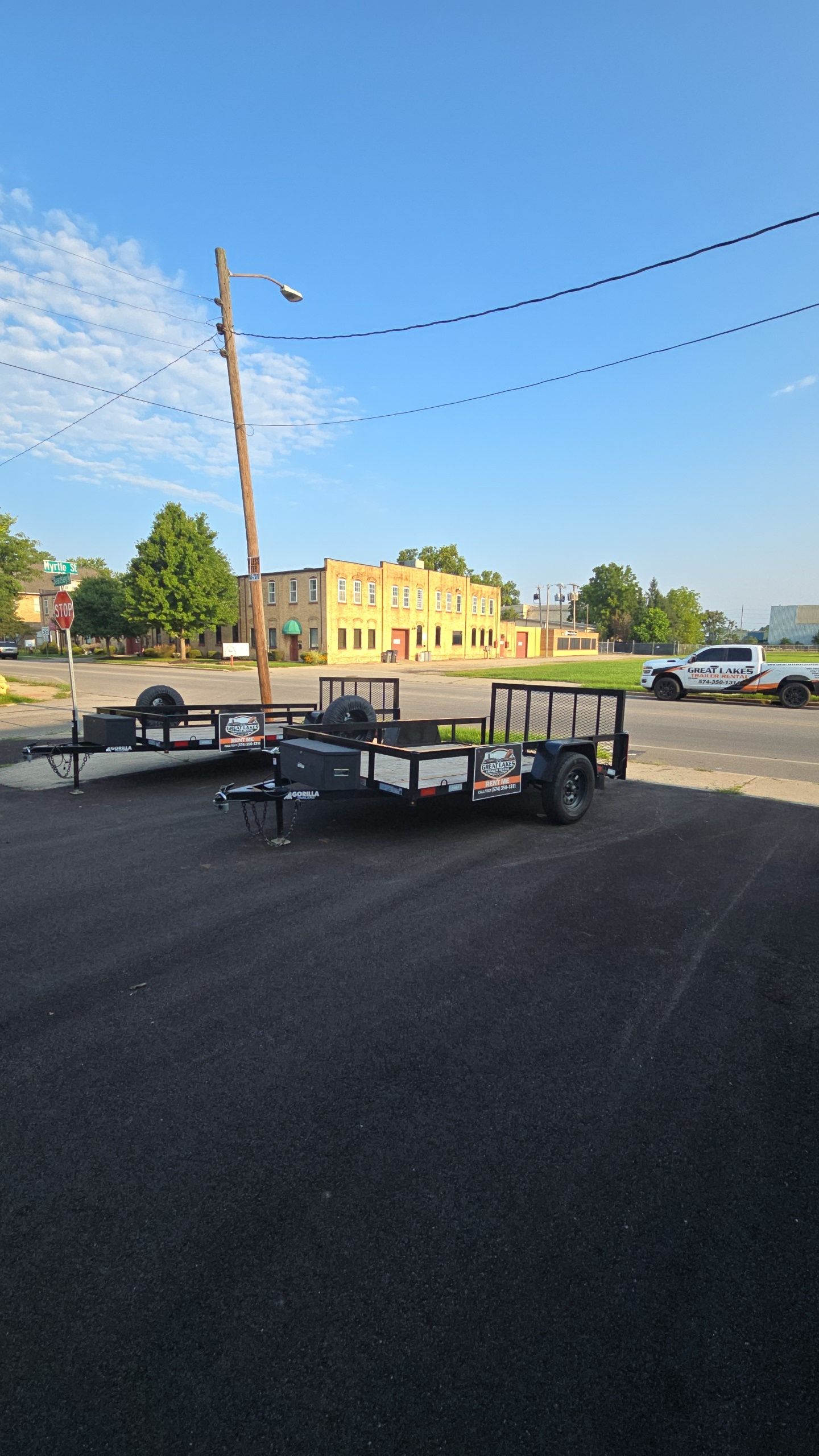 Trailer with stacked chairs in a parking lot, with a yellow building and utility poles in the background.