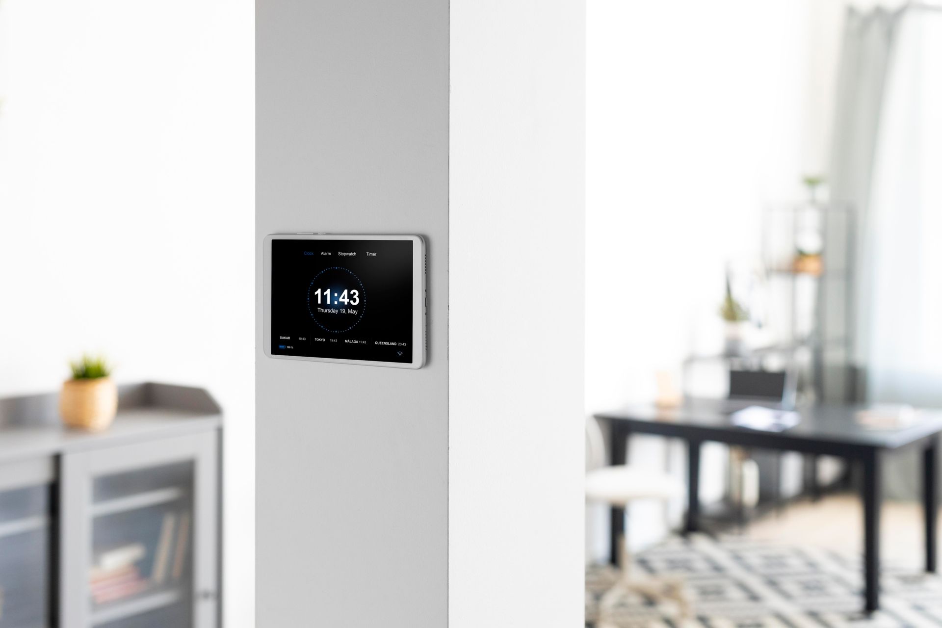 Wall-mounted touchscreen thermostat on a white pillar in a modern living room
