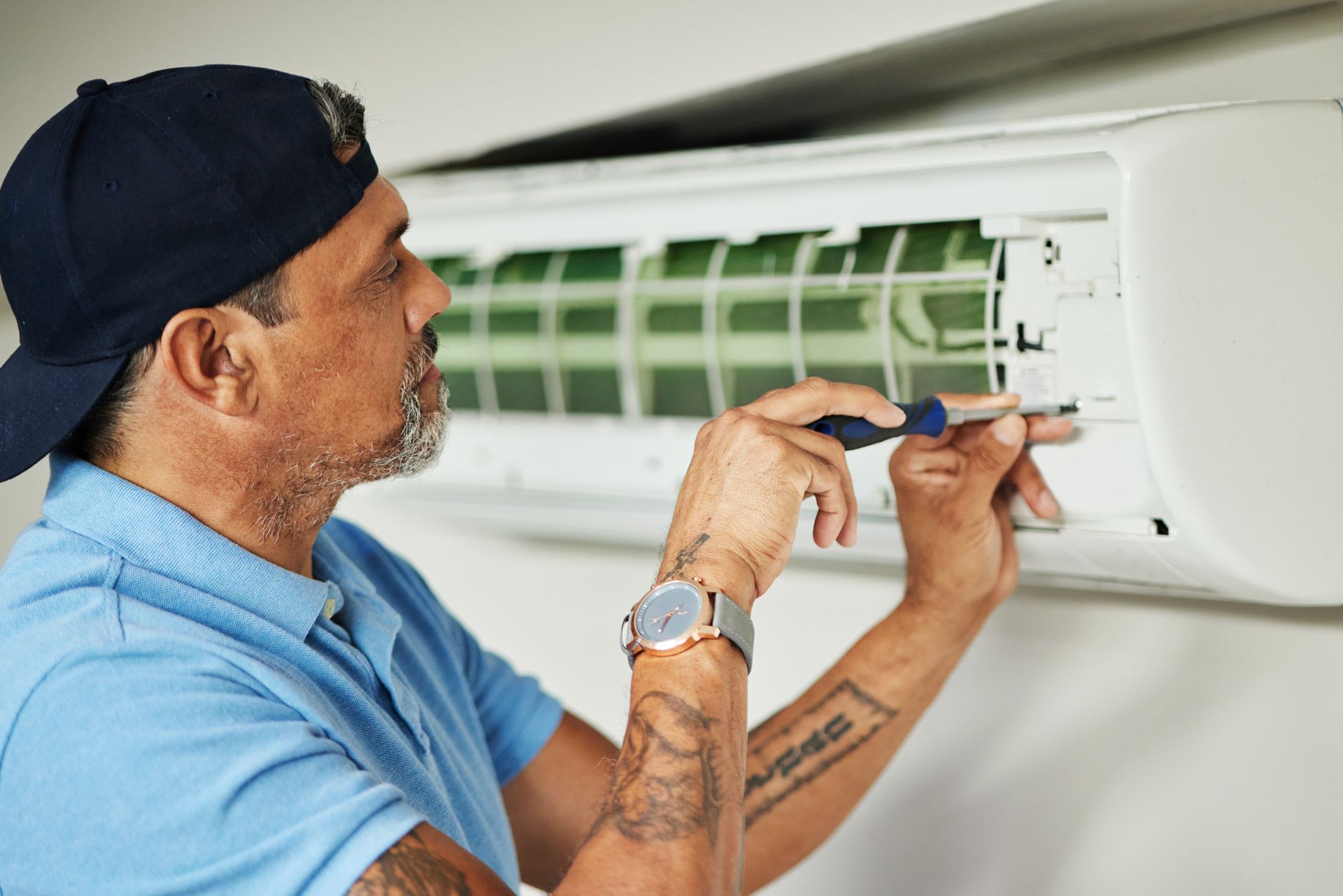 Technician repairing a wall-mounted air conditioner with a screwdriver