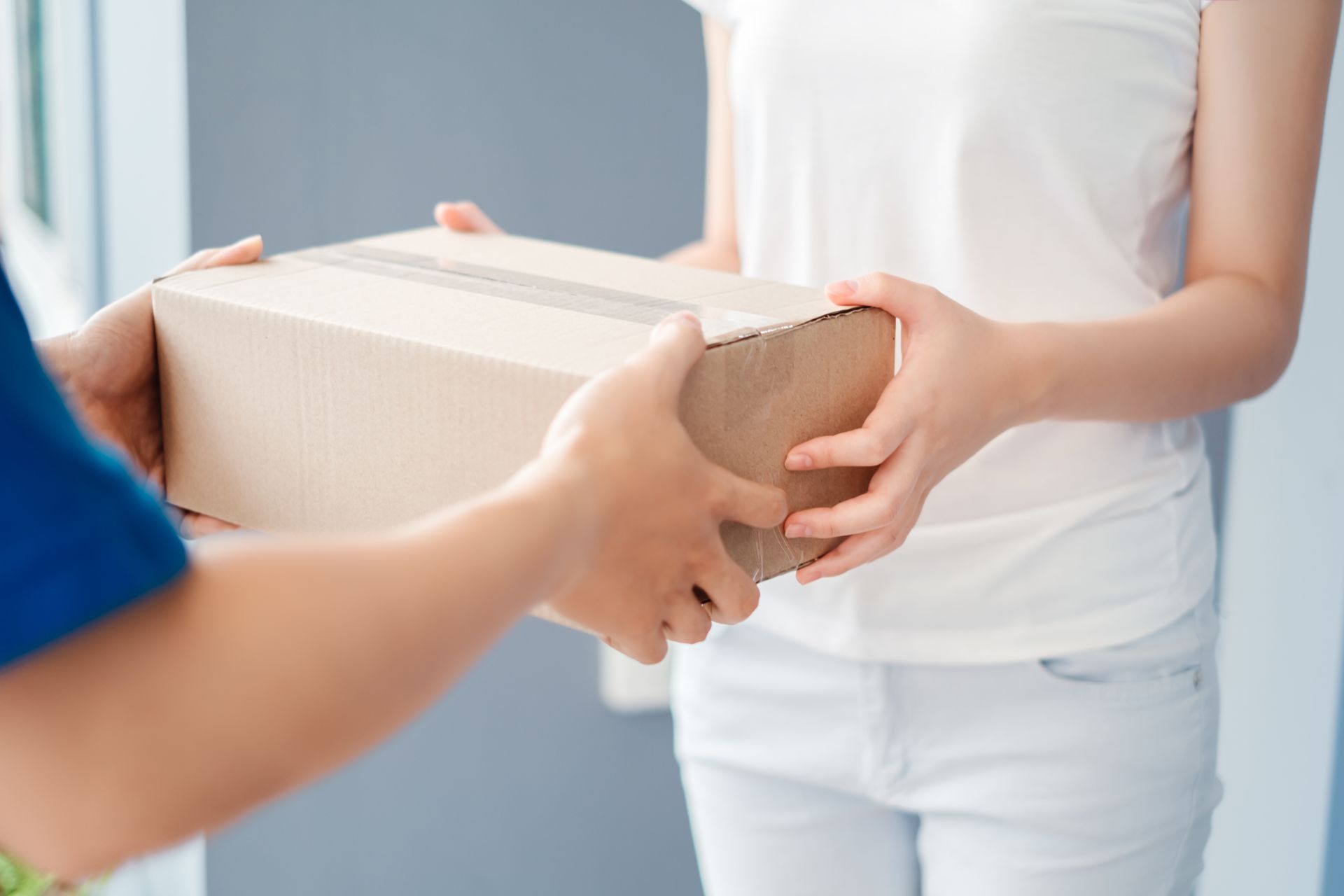 Man delivering a package to a woman with a zoom on the package itself.