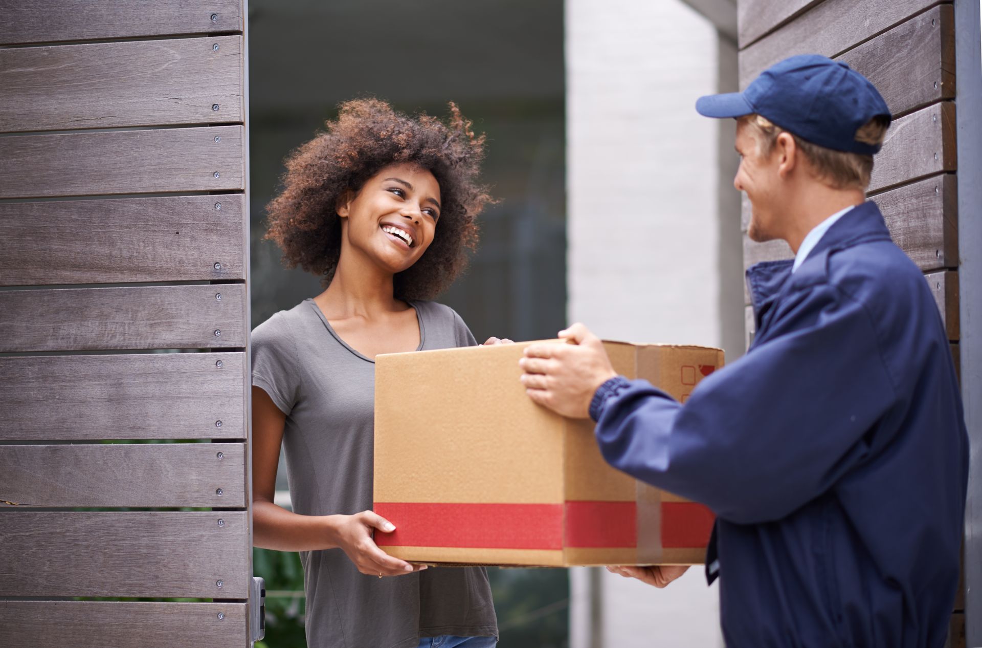 Woman receiving a delivery from a courier at her front door.