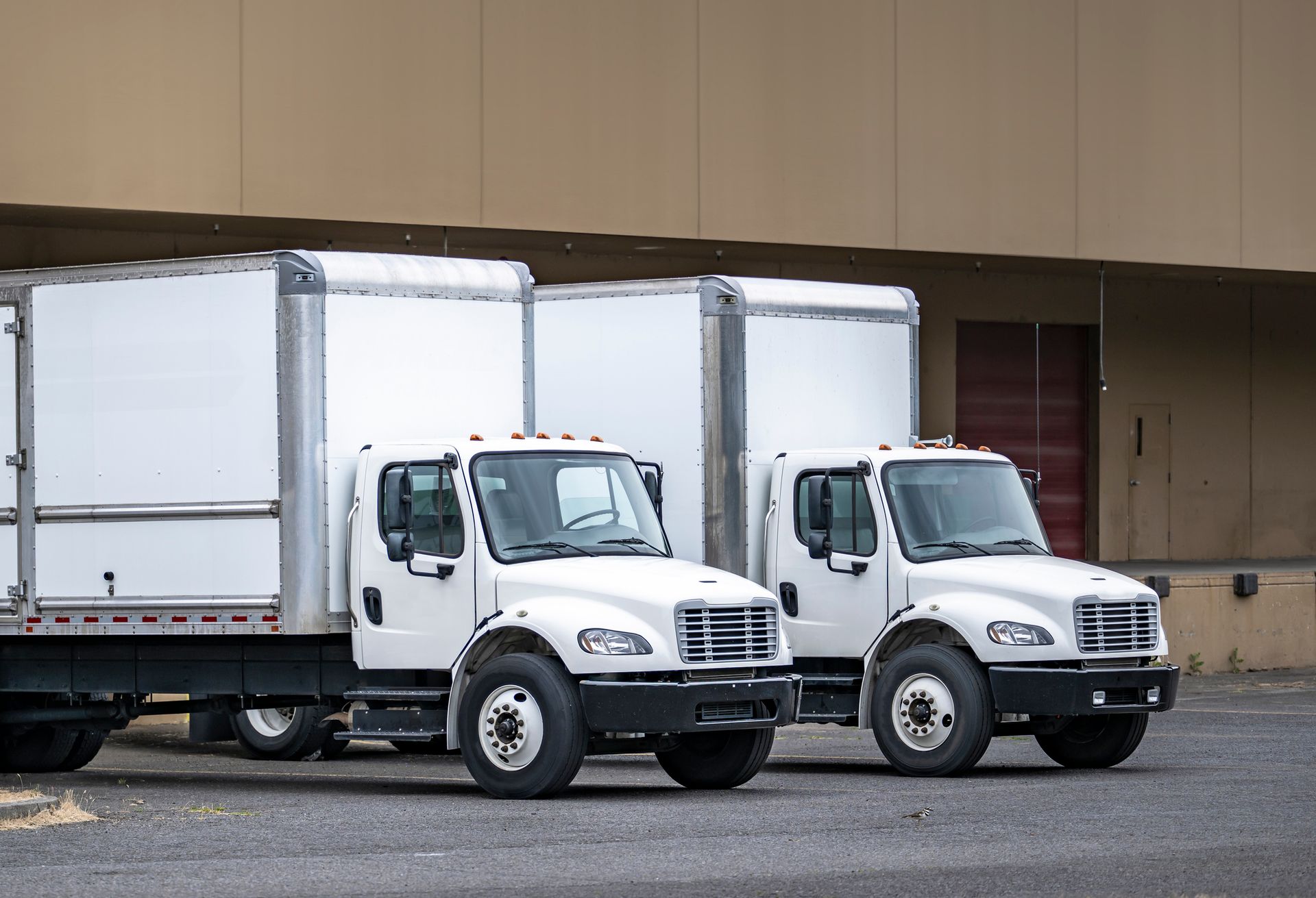 Pallets of boxes being loaded into a semi-truck at a warehouse loading dock.