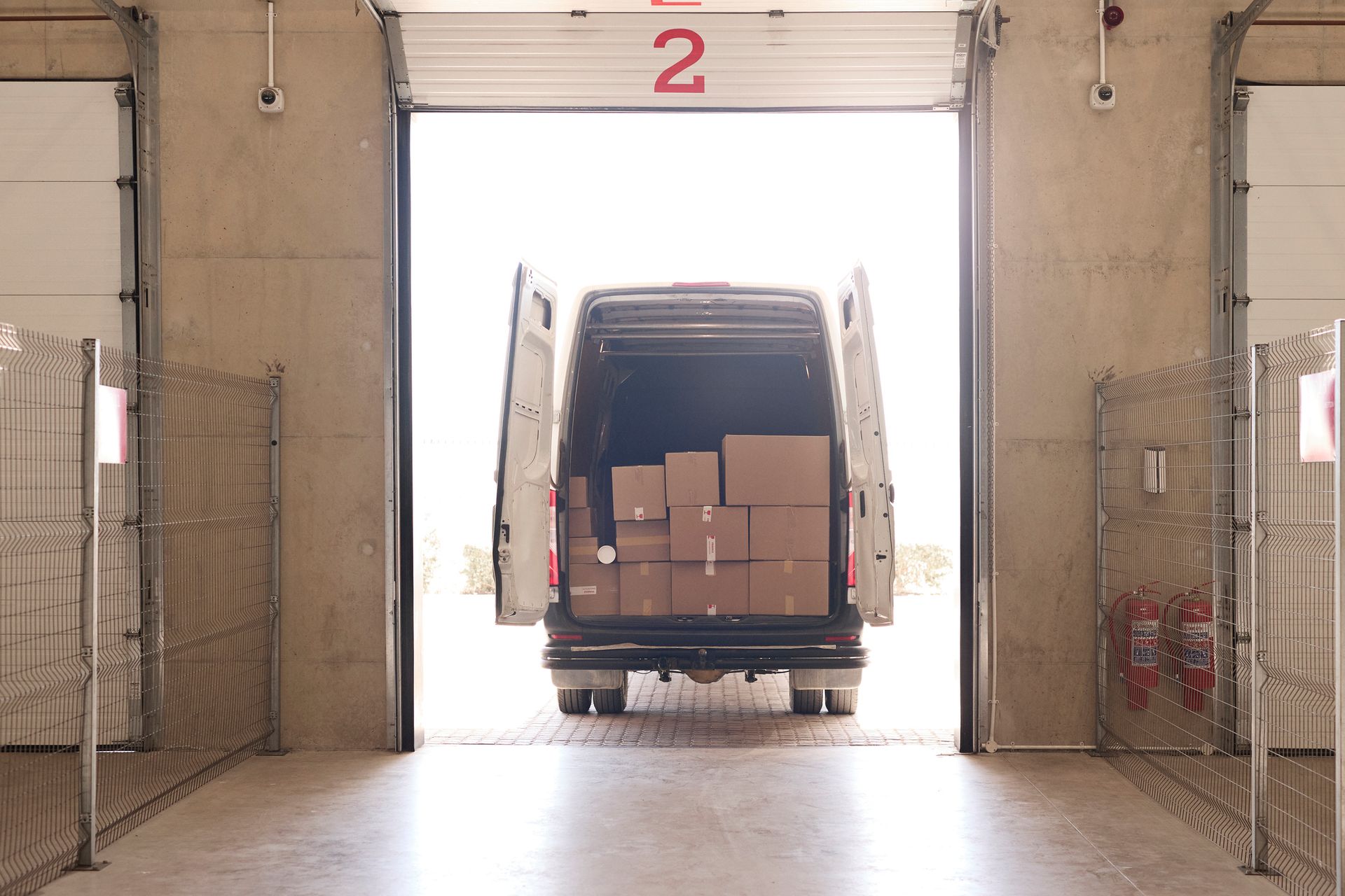 Two white semi-trucks loading at a modern warehouse with reflective windows under a yellow awning. Two white semi-trucks loading at a modern warehouse with reflective windows under a yellow awning.