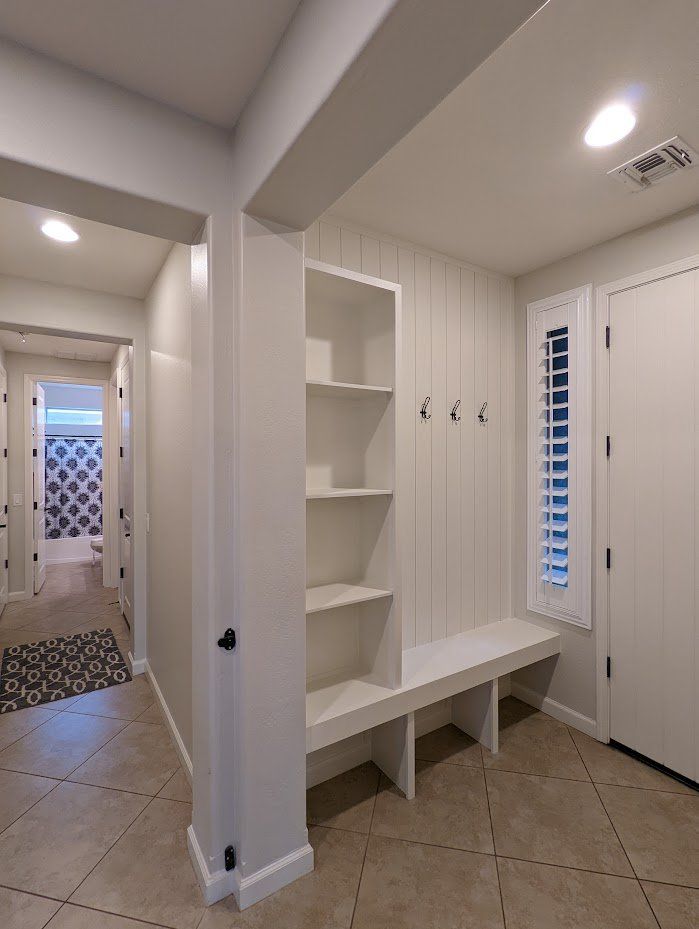 A hallway in a house with a bench and shelves