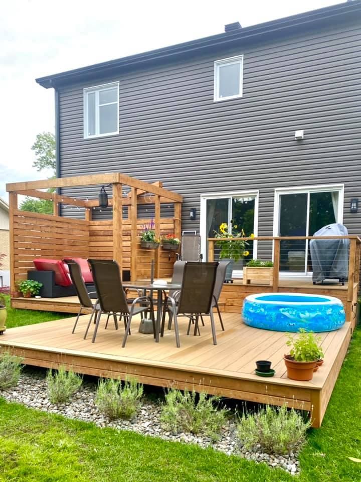 Une terrasse en bois avec une table et des chaises et une piscine dans la cour d'une maison.