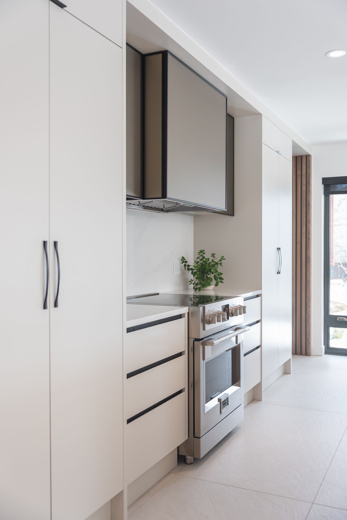 Une cuisine avec armoires blanches et appareils électroménagers en acier inoxydable.