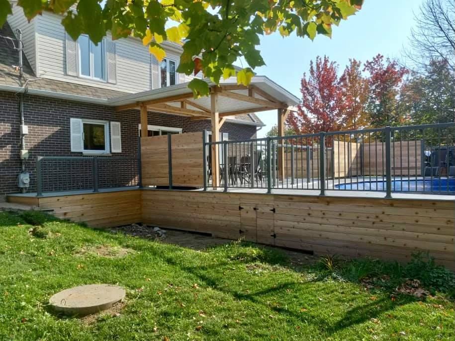 Une maison avec une terrasse en bois et une piscine dans la cour.