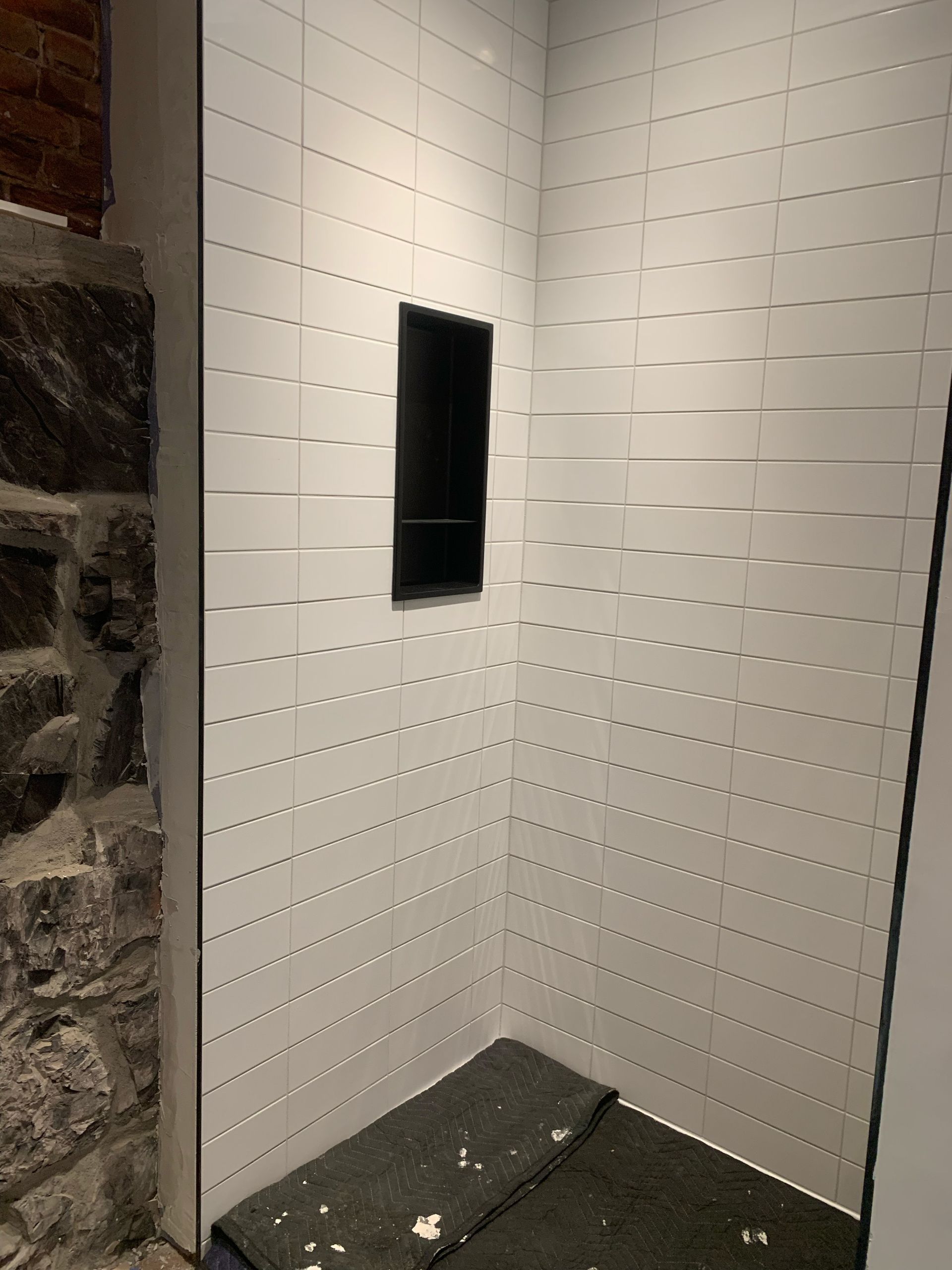 Une salle de bain avec carrelage blanc et mur en pierre.
