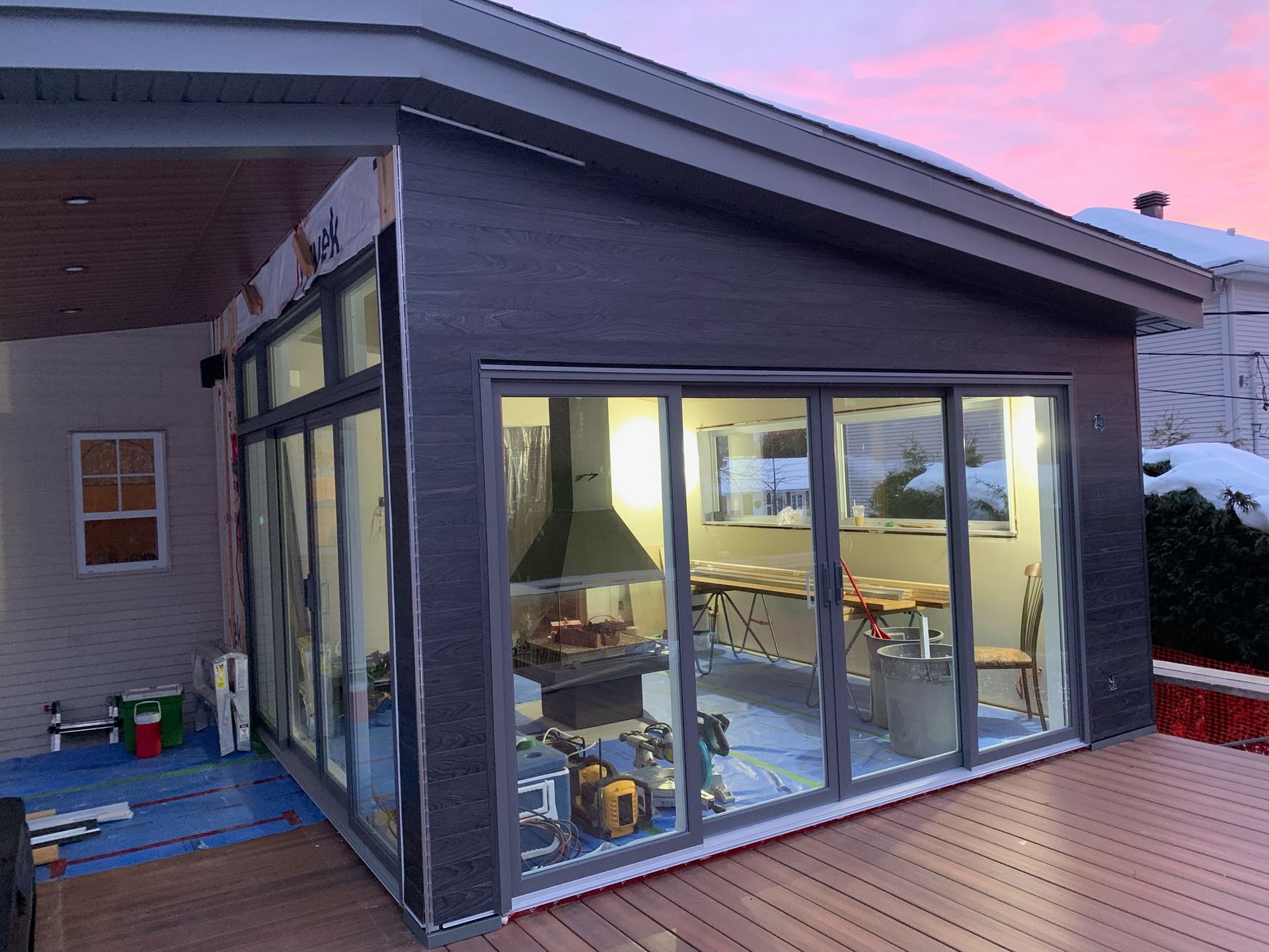 Une maison avec beaucoup de fenêtres et un coucher de soleil en arrière-plan