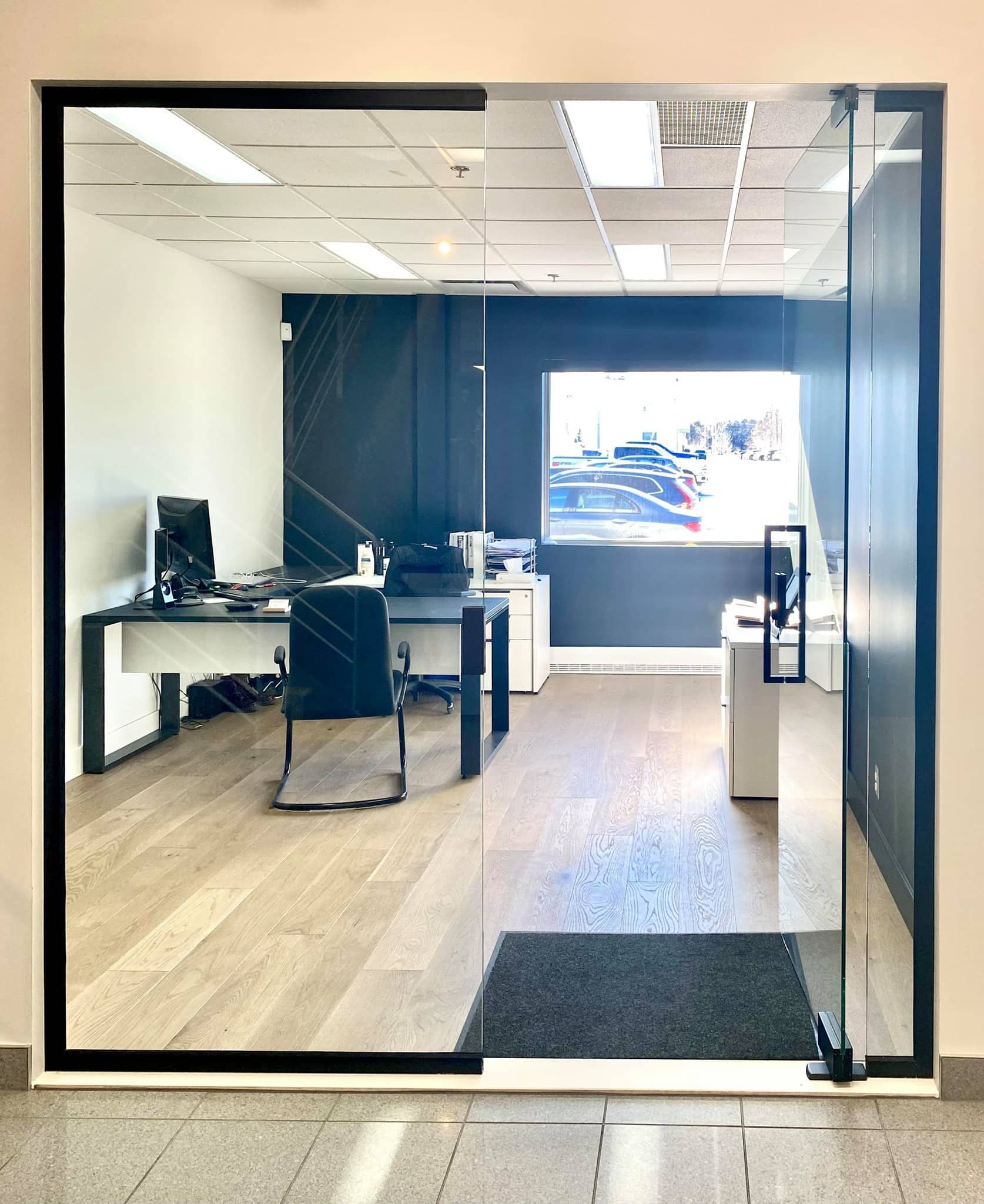 Une porte vitrée s'ouvre sur une pièce avec un bureau et des chaises