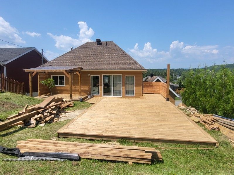 Une terrasse en bois est en cours de construction devant une maison.