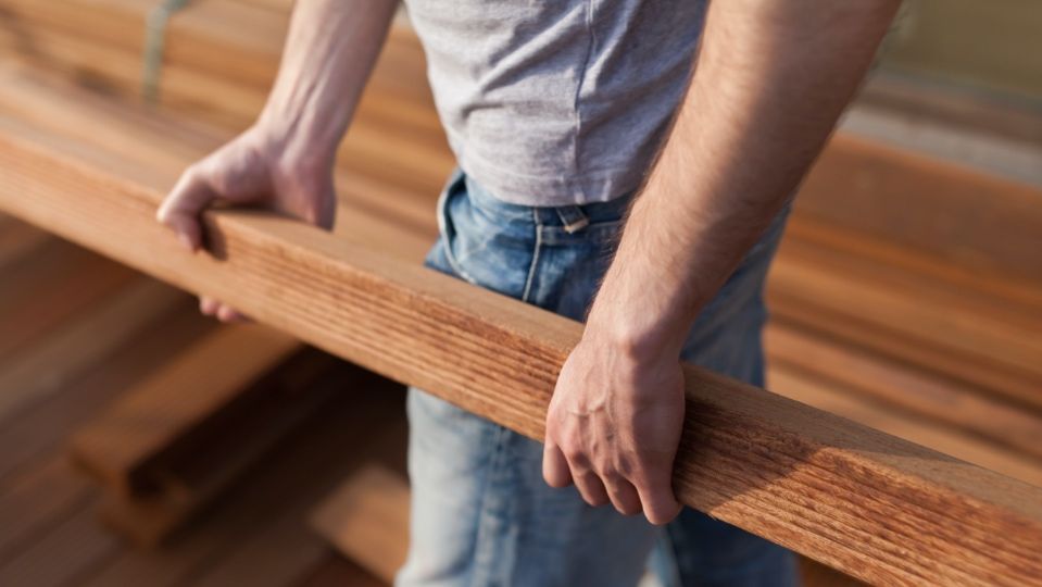 Un homme tient un morceau de bois dans ses mains.