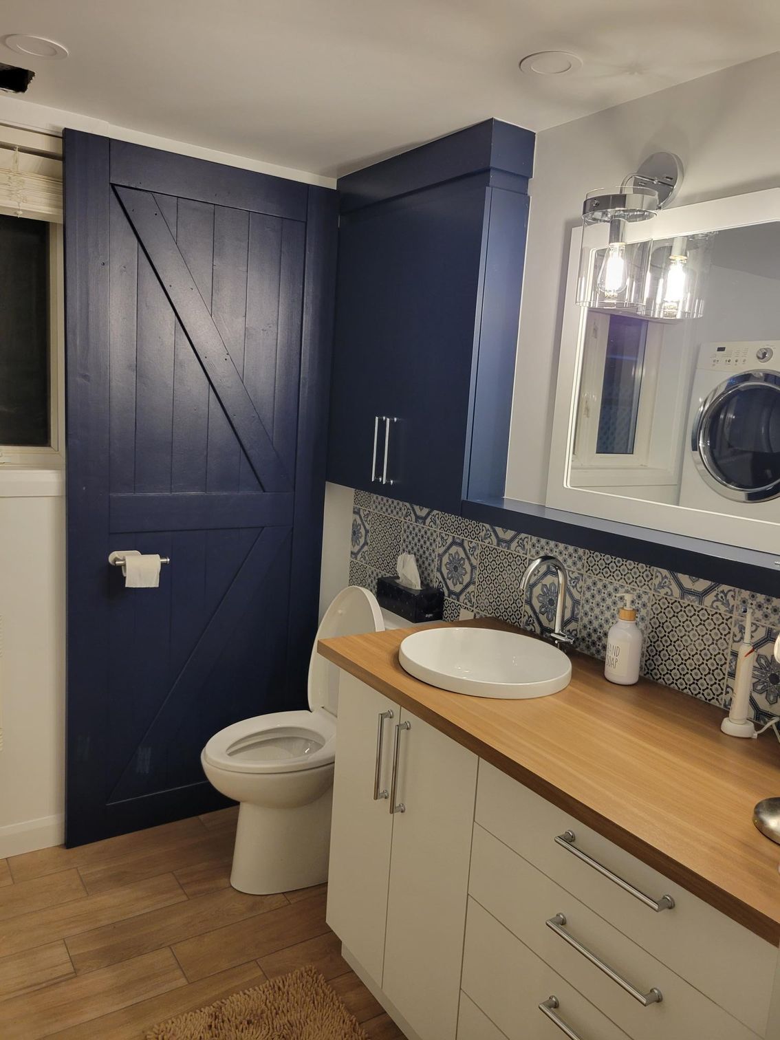 Salle de bain bleue et blanche avec un comptoir en bois et une porte de grange coulissante bleu marine.