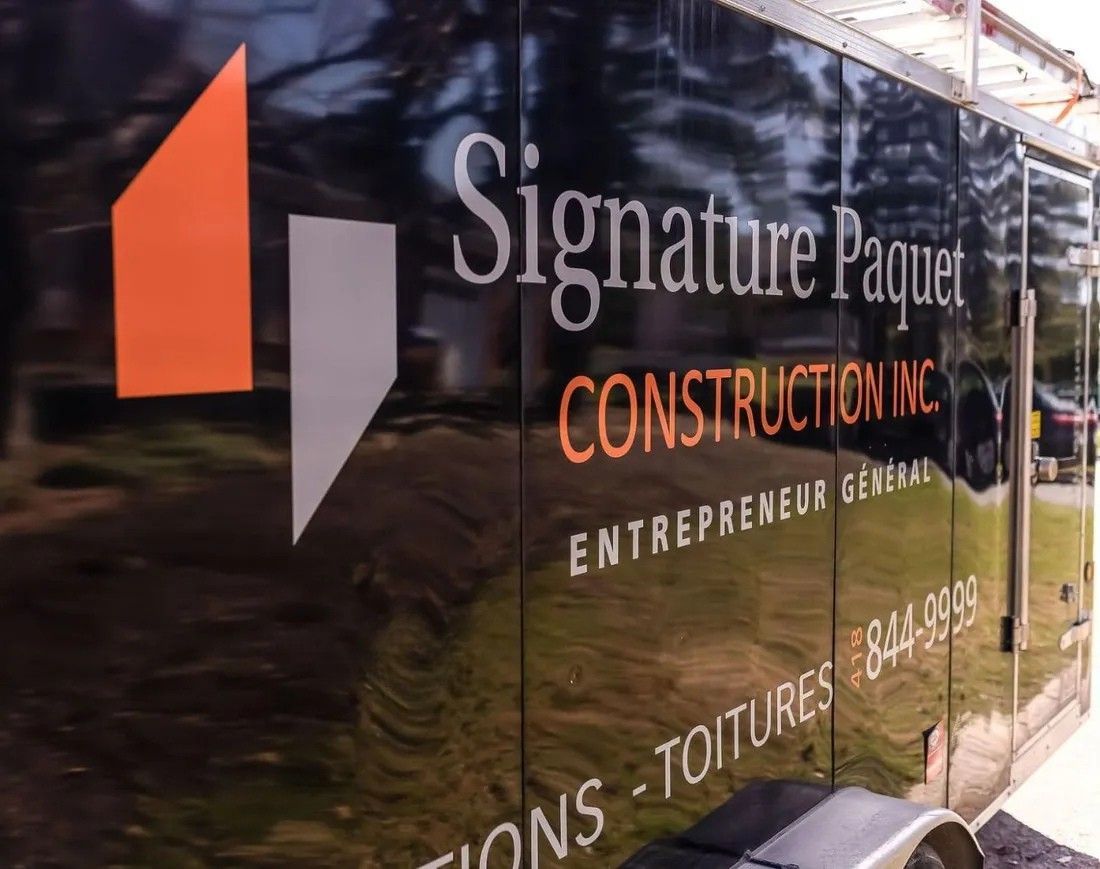 Une remorque paquet signature construction inc est stationnée sur le bord de la route.