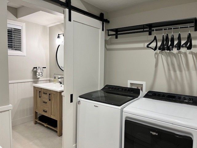 Buanderie avec lave-linge, sèche-linge et accès à une salle de bain. Couleurs blanc et noir.
