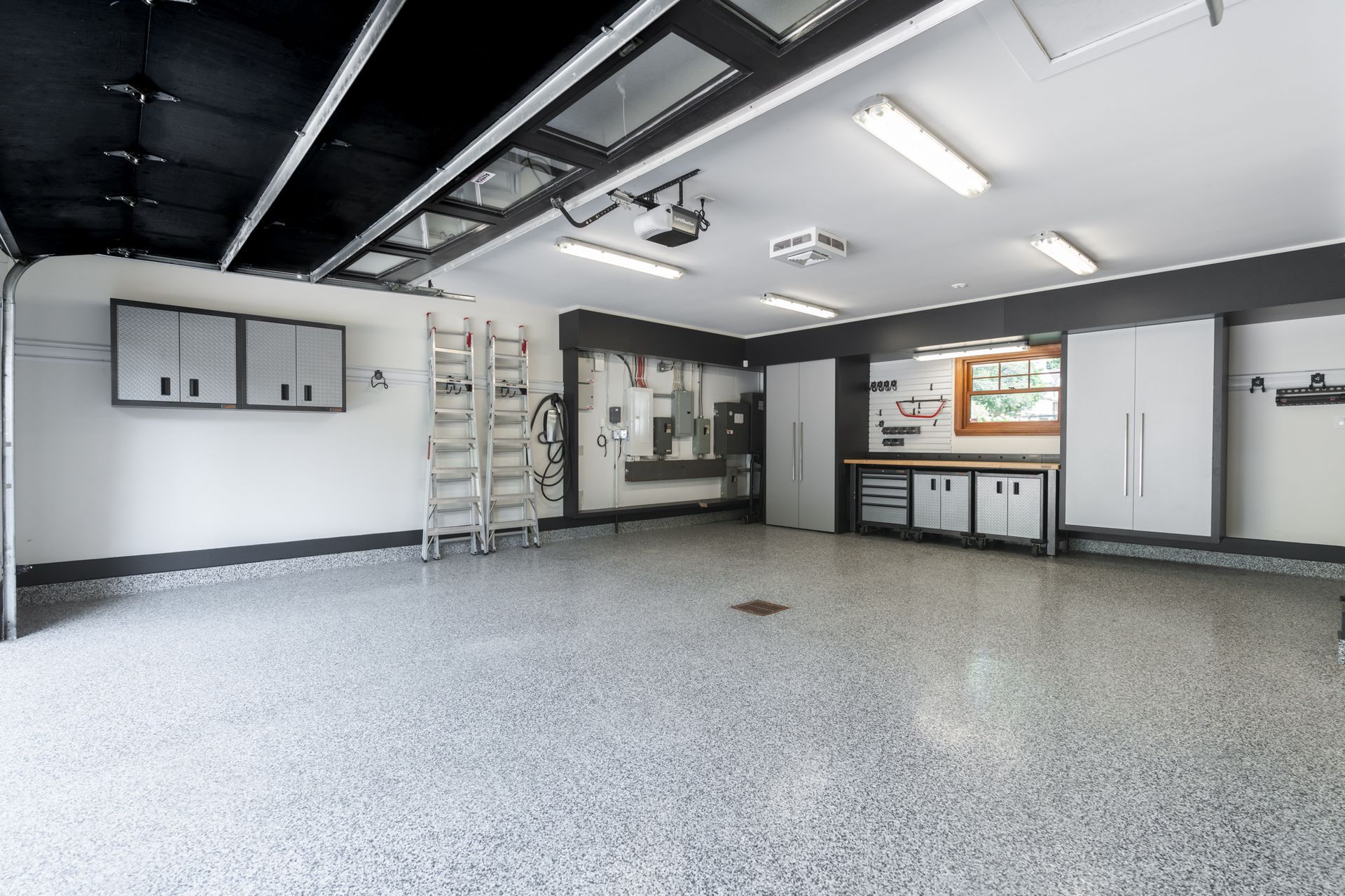 Garage vide avec sol et armoires en époxy. Plafond noir, murs blancs.