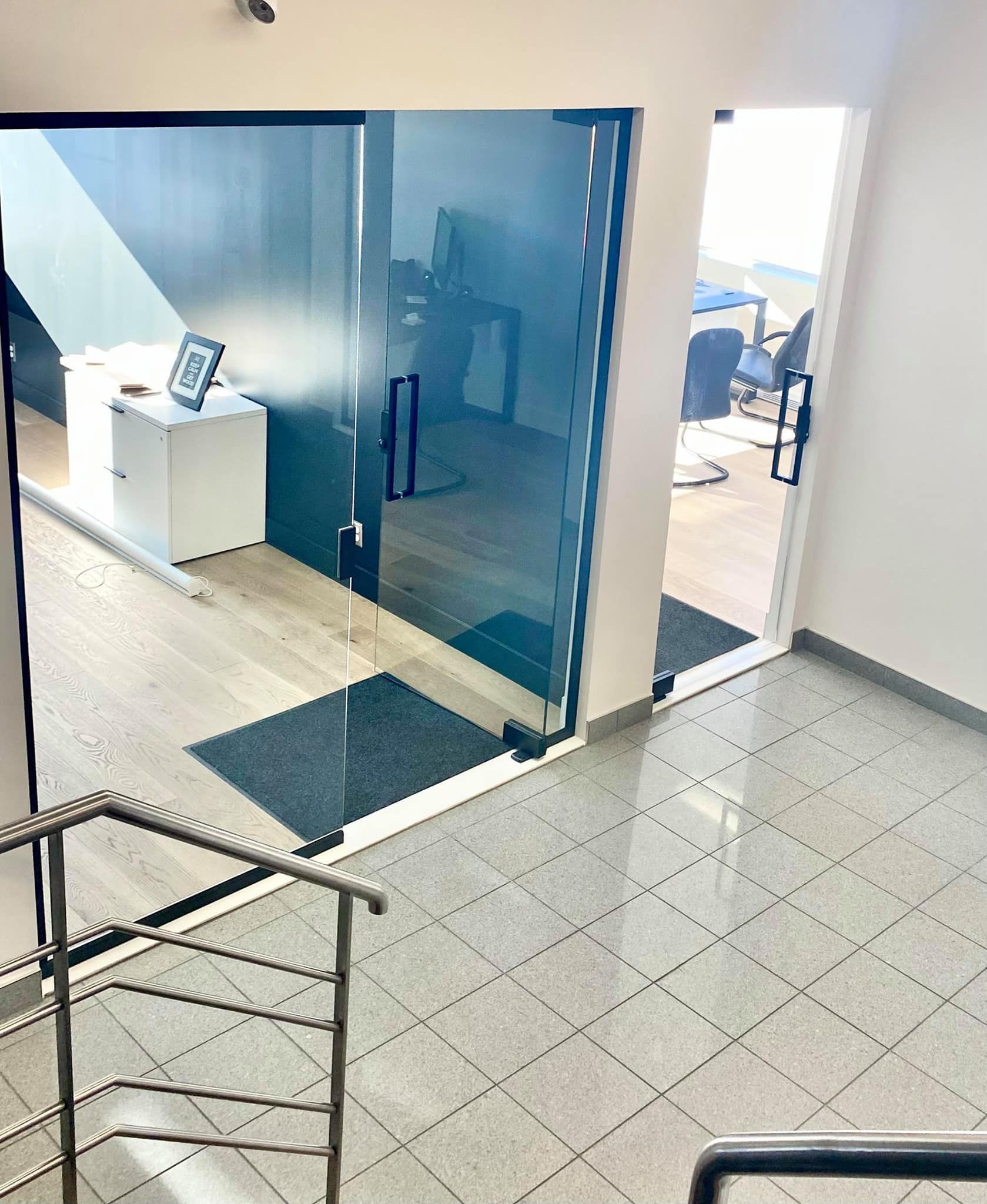 Une pièce avec une porte vitrée et des escaliers qui y mènent