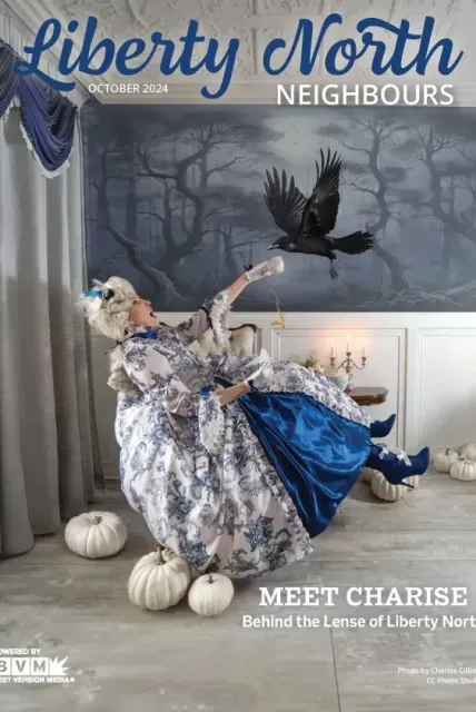 Charise posing in blue dress amid white pumpkins and a flying black bird in a moody Liberty North Neighbours scene