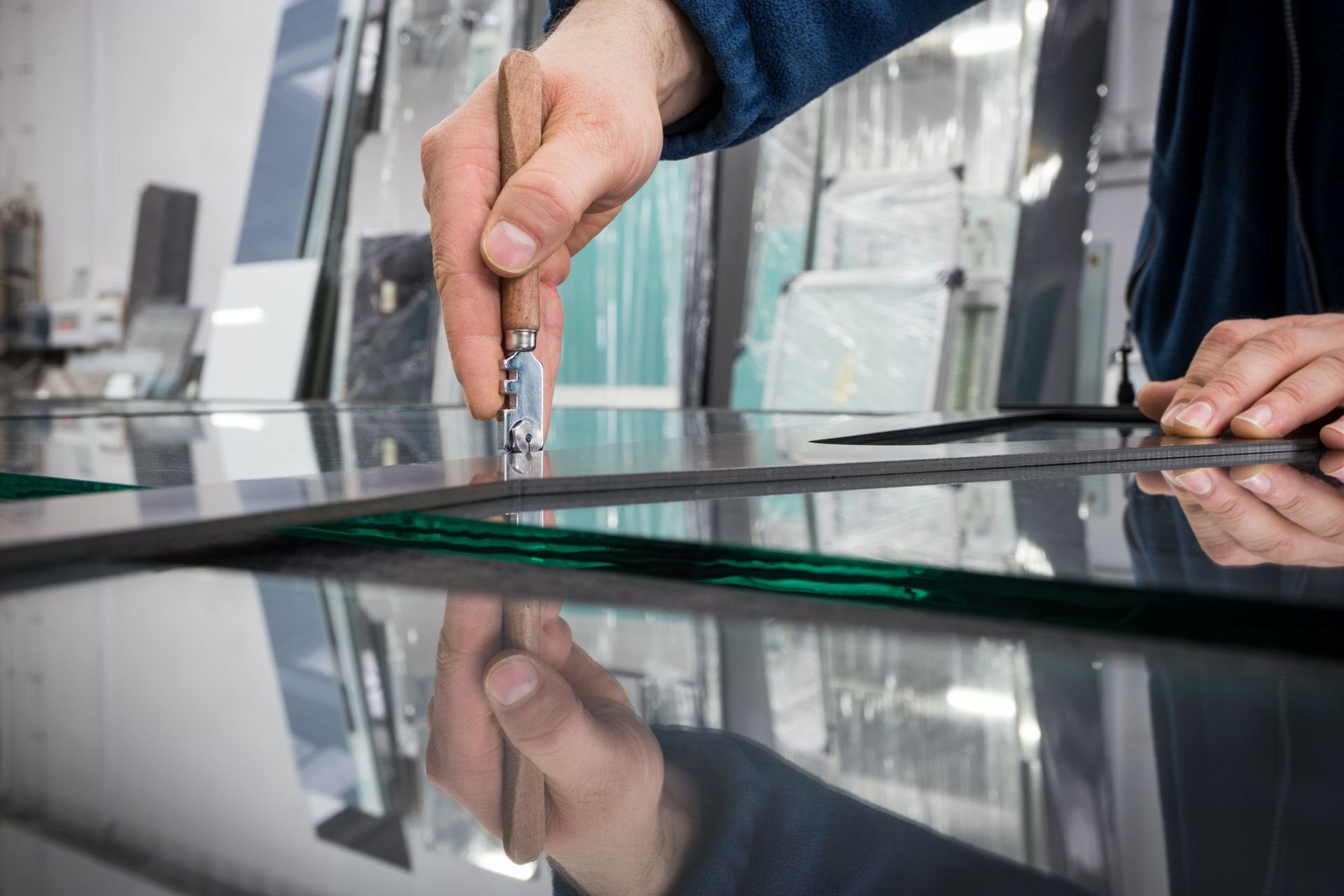 View of a glazier cutting a glass panel with a tool.