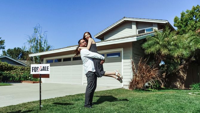 Couple embracing in front of a suburban house with a 