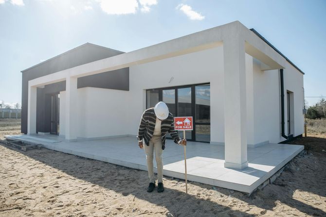 Modern white house exterior with a person standing on the front walkway under bright sun