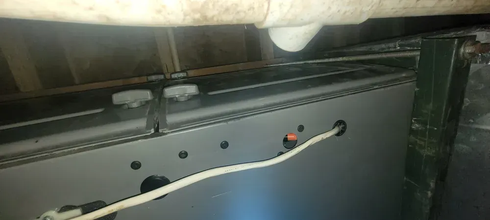 A close-up view of an electrical wiring setup with a white cable, metal parts, and a pipe.