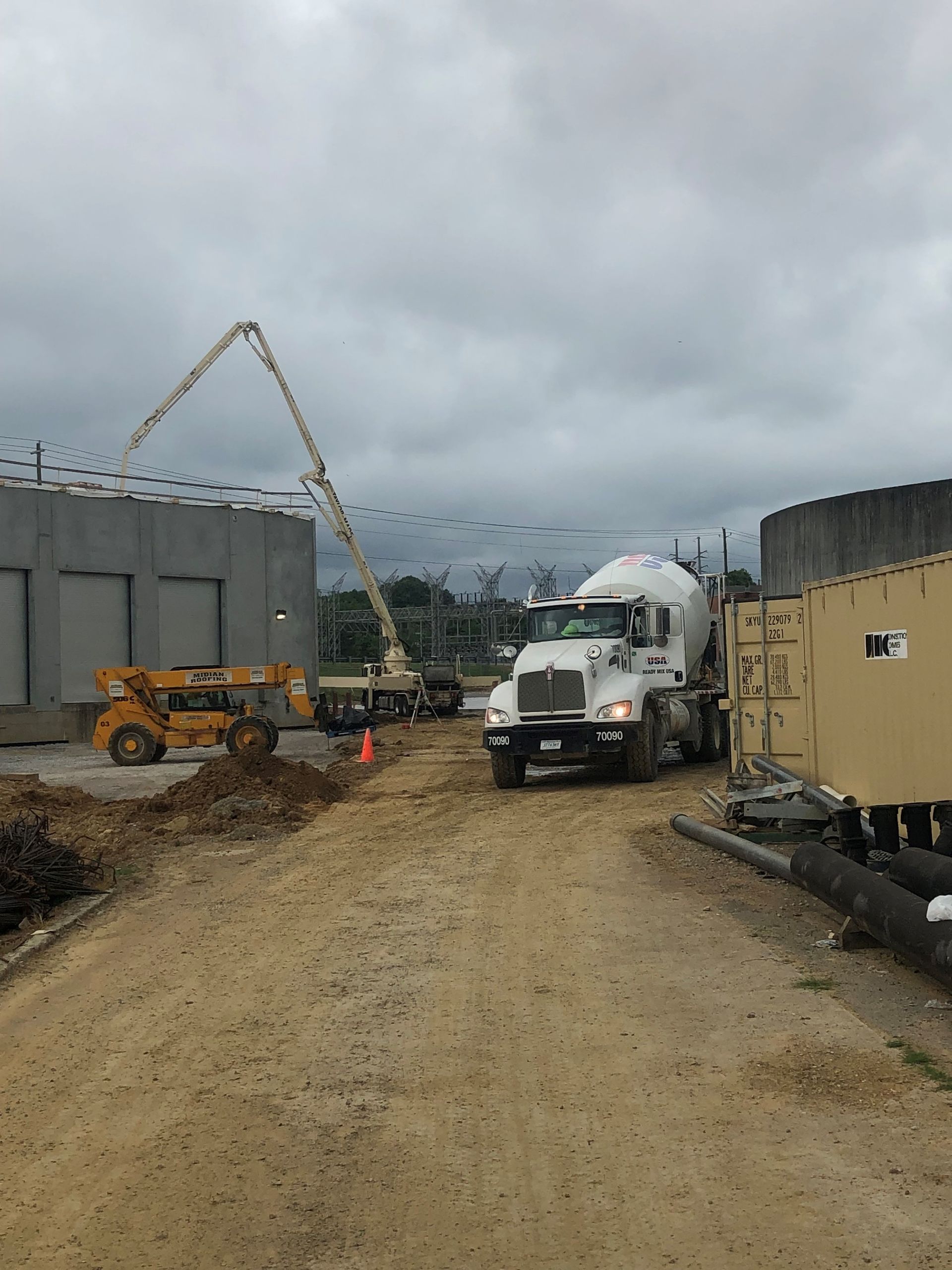 A Cement Truck is Driving Down a Dirt Road in Front of a Building Under Construction | Tallapoosa, GA | Taylor-Made Pumping