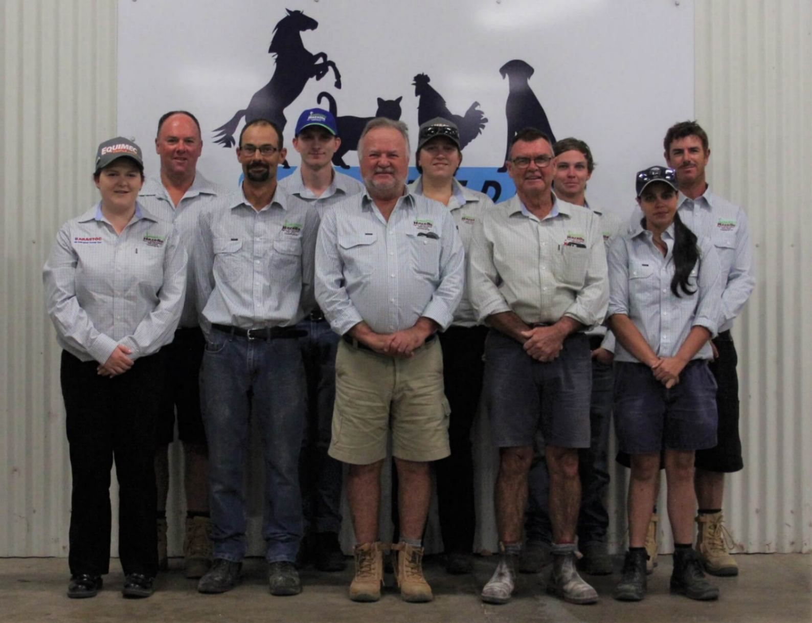 A Group of People Standing in Front of A Sign with Horses and Dogs on It — Hazells Farm & Fertilizer Services in Taminda, NSW