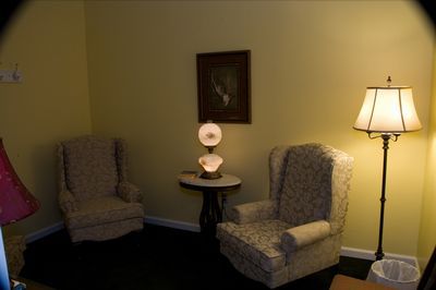 a living room with two chairs and a lamp