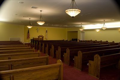 an empty church with wooden benches and a red carpet .