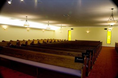 a church with rows of wooden benches and a red carpet .