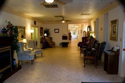 a long hallway with chairs , a fireplace and a ceiling fan .