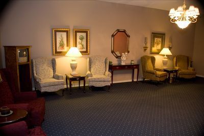 a living room with chairs , tables , lamps and a chandelier .
