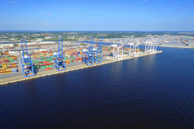 An aerial view of a harbor filled with containers and cranes.