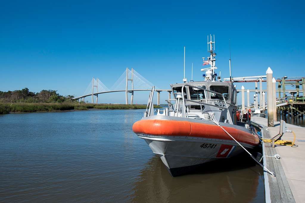 A boat is docked at a dock with a bridge in the background.