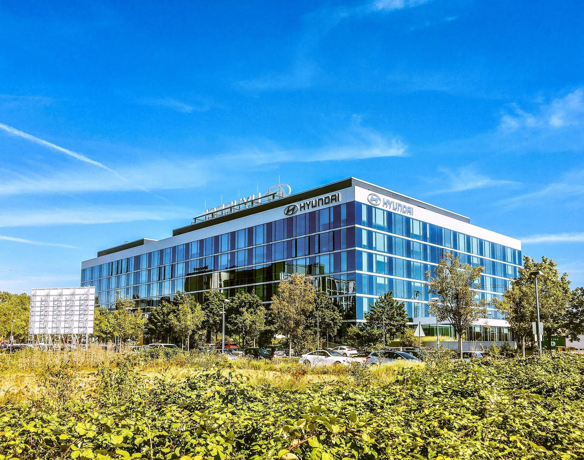 A large building with a lot of windows is surrounded by trees and bushes.