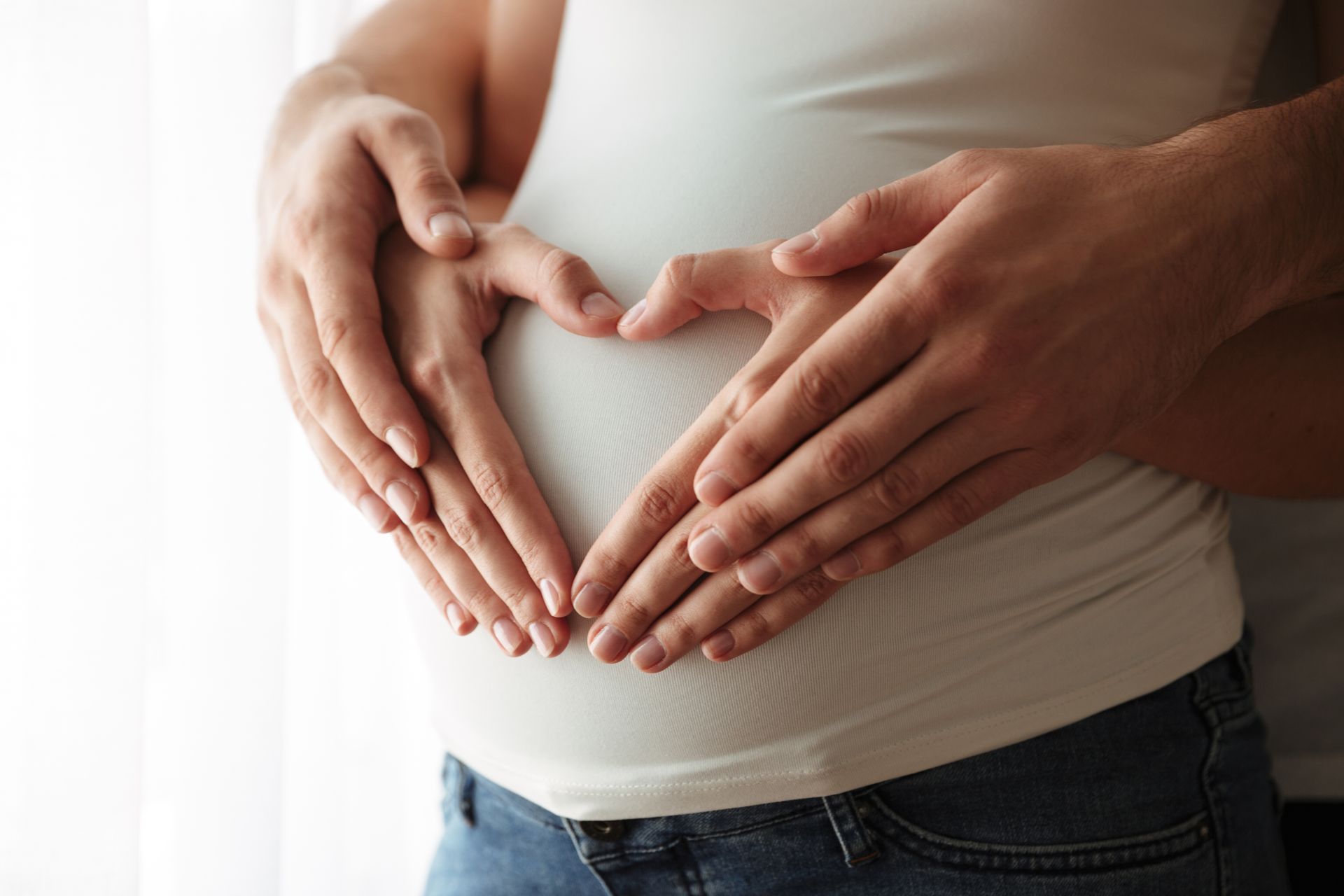a man and a woman are making a heart shape with their hands on a pregnant woman 's belly
