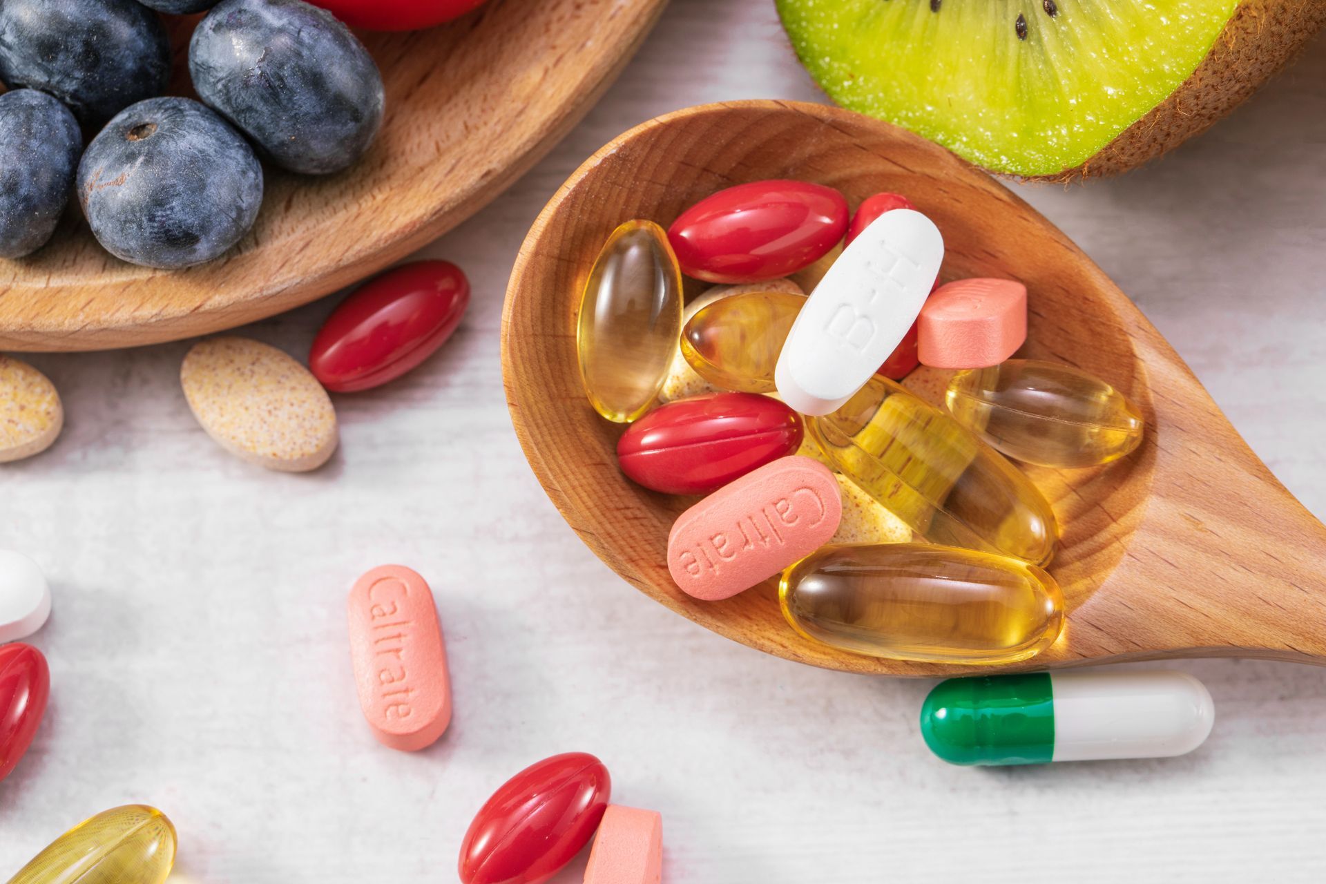 a wooden spoon filled with different colored caltrate pills