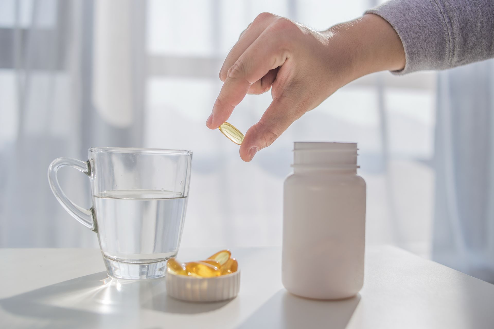 a person taking a pill next to a glass of water
