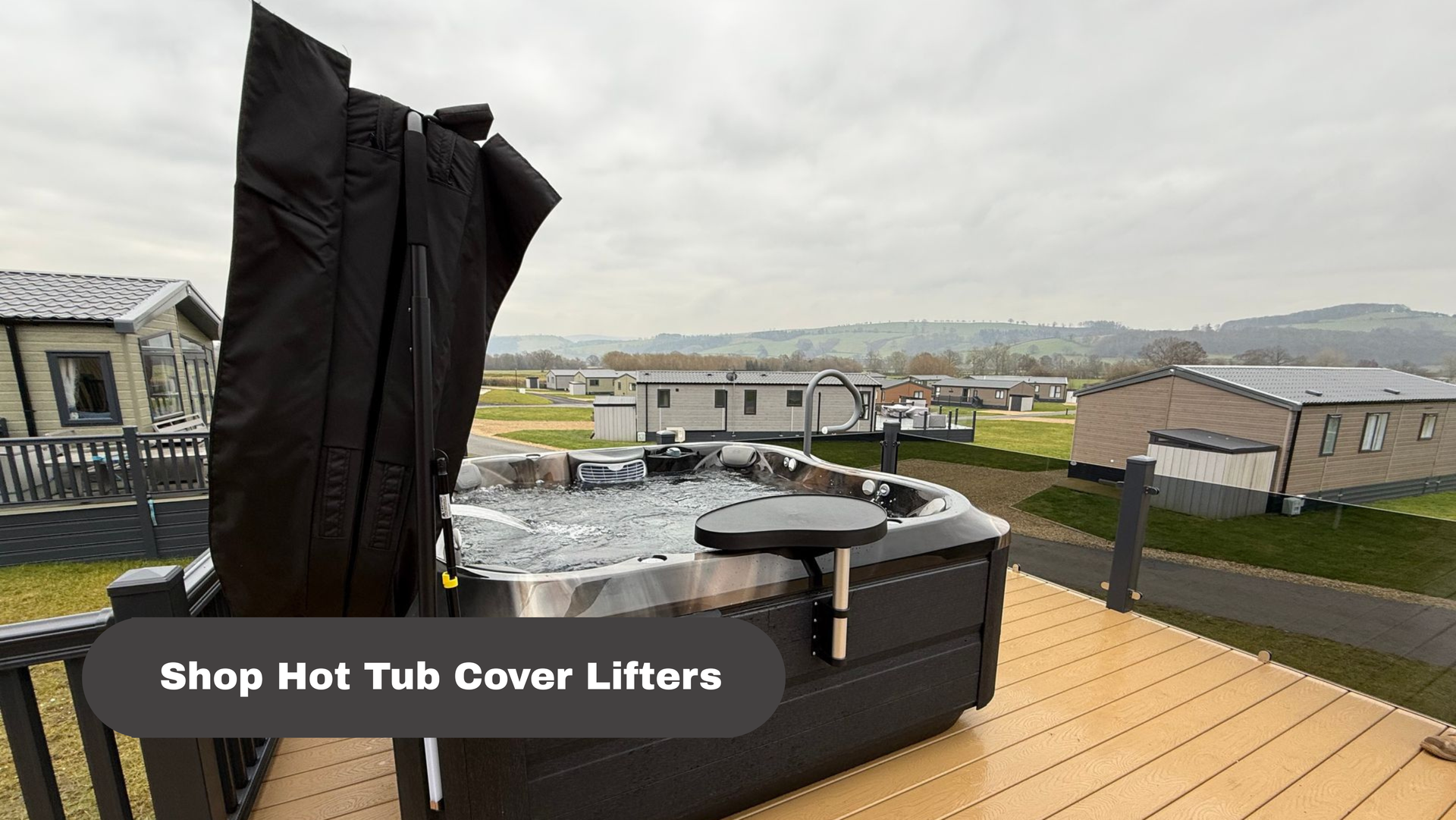 Hot tub cover lifter on a deck with a raised black cover and suburban homes in the background